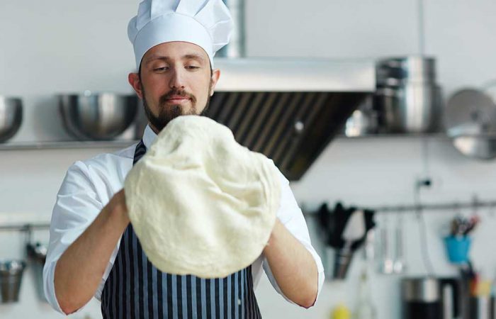 Persona che impara a cucinare impastando pizza o pane