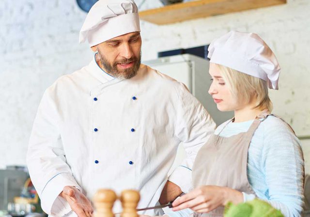 professore che insegna alla studentessa in un istituto alberghiero